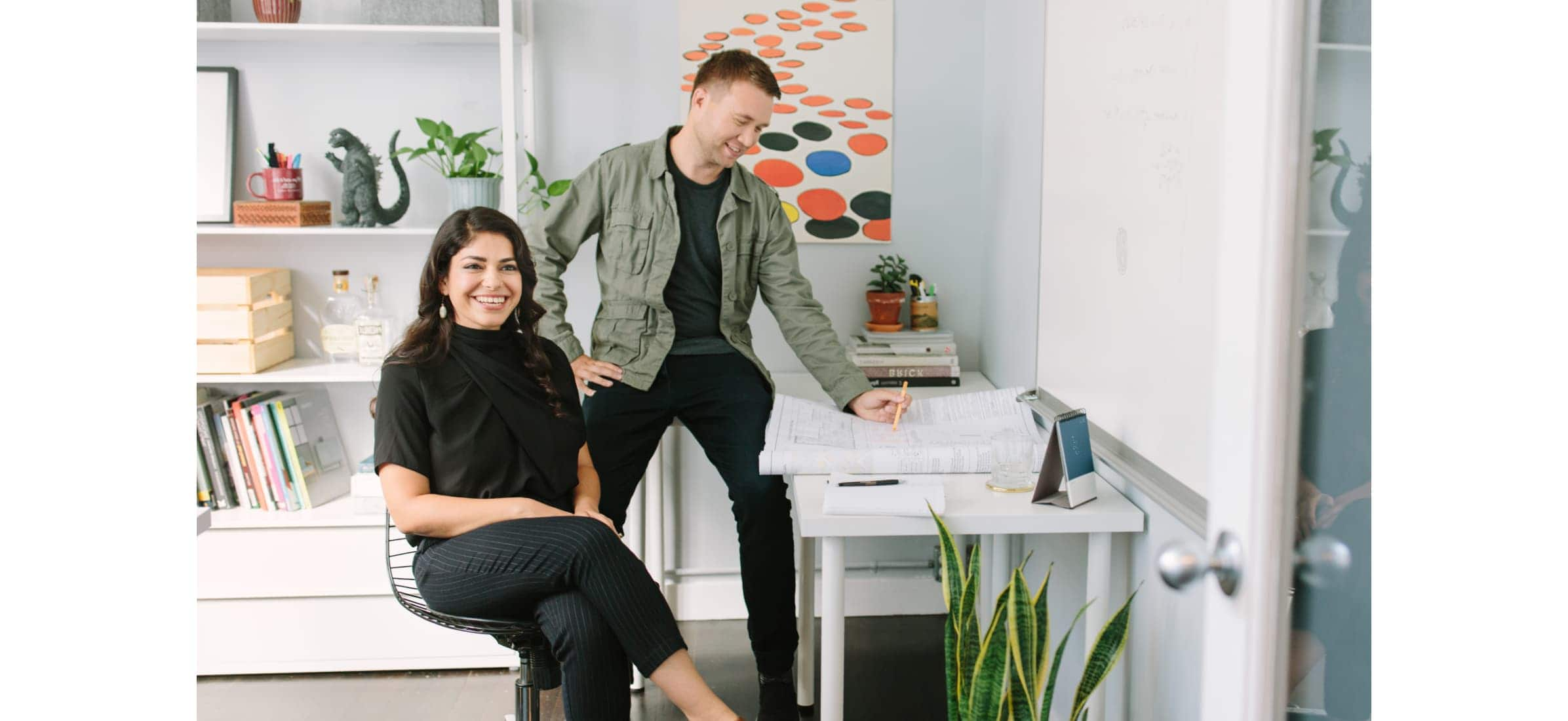 Nastaran Mousavi and Dane Bunton, owners of Studio BANAA, sitting in their studio laughing.